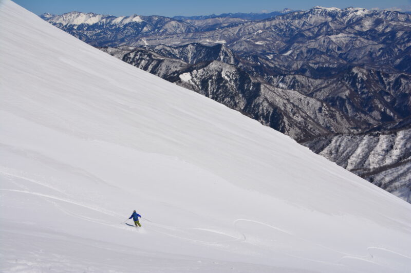 谷川岳を滑り降りるスキーヤー
