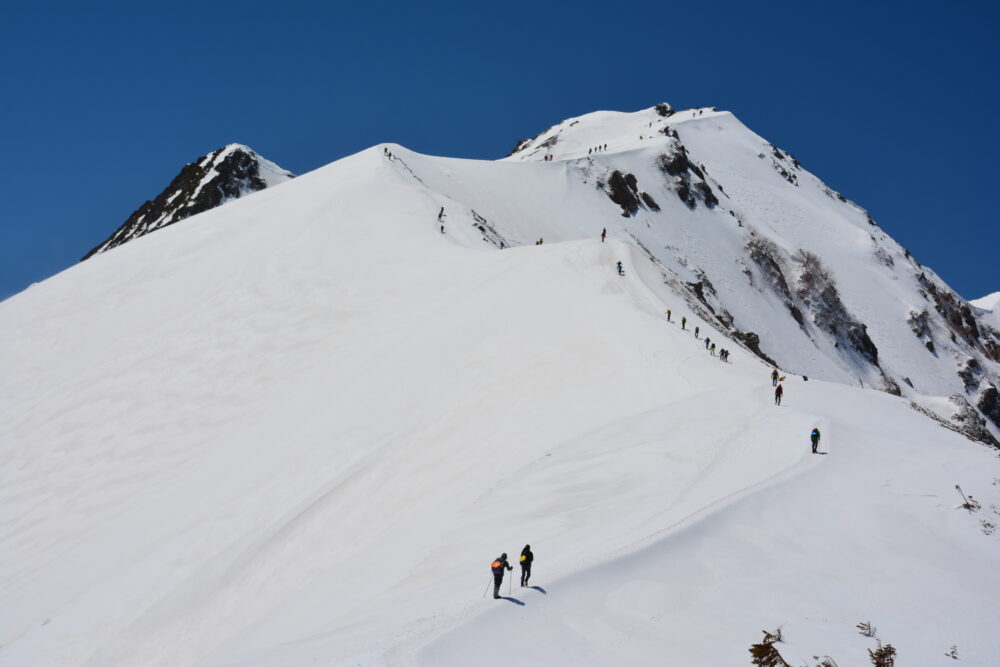 雪の唐松岳を登登山者たち