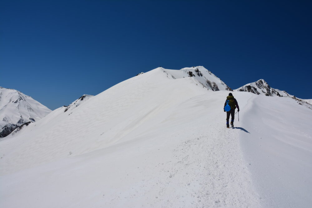 雪の唐松岳を登登山者たち