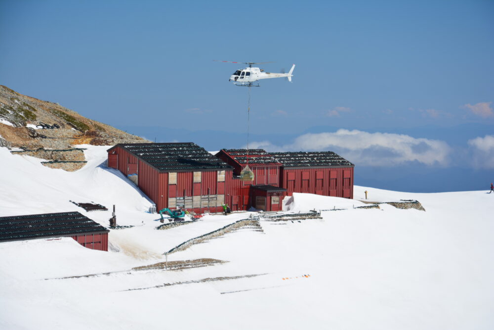 残雪期の唐松岳頂上山荘で荷揚げするヘリコプター