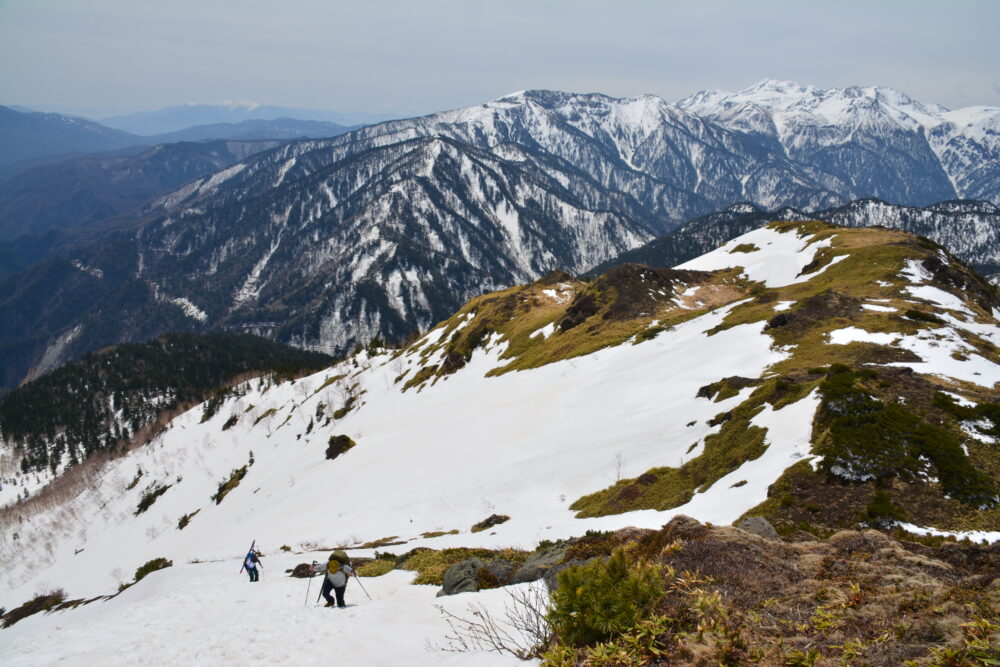 残雪期の焼岳を登る登山者と乗鞍岳