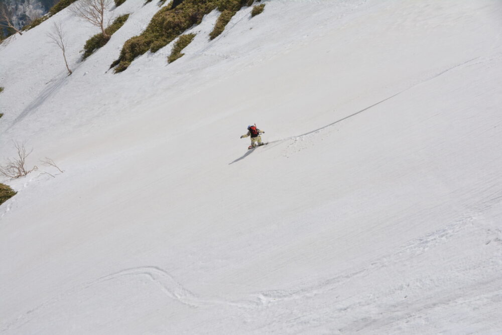 残雪期の焼岳を滑るスノーボーダー