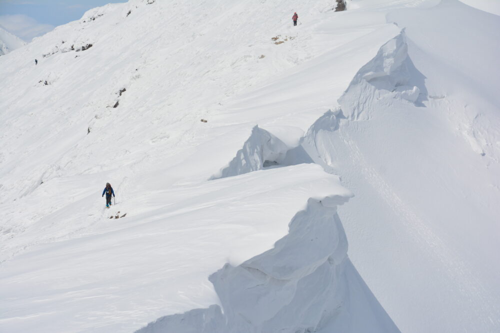 冬の谷川岳を歩く登山者と雪庇
