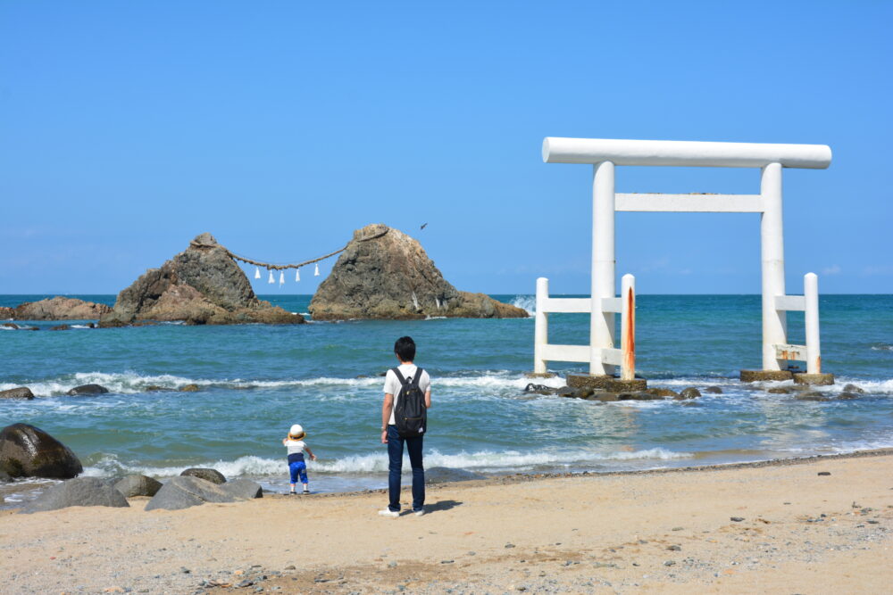 糸島の二見ヶ浦海岸の白い鳥居と夫婦岩と遊んでいる親子