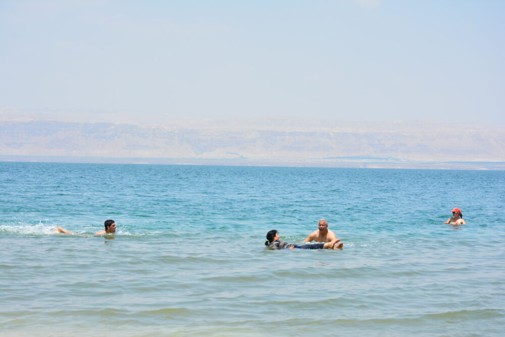 ヨルダン側の死海にあるアンマンビーチで泳いだり浮いている人々