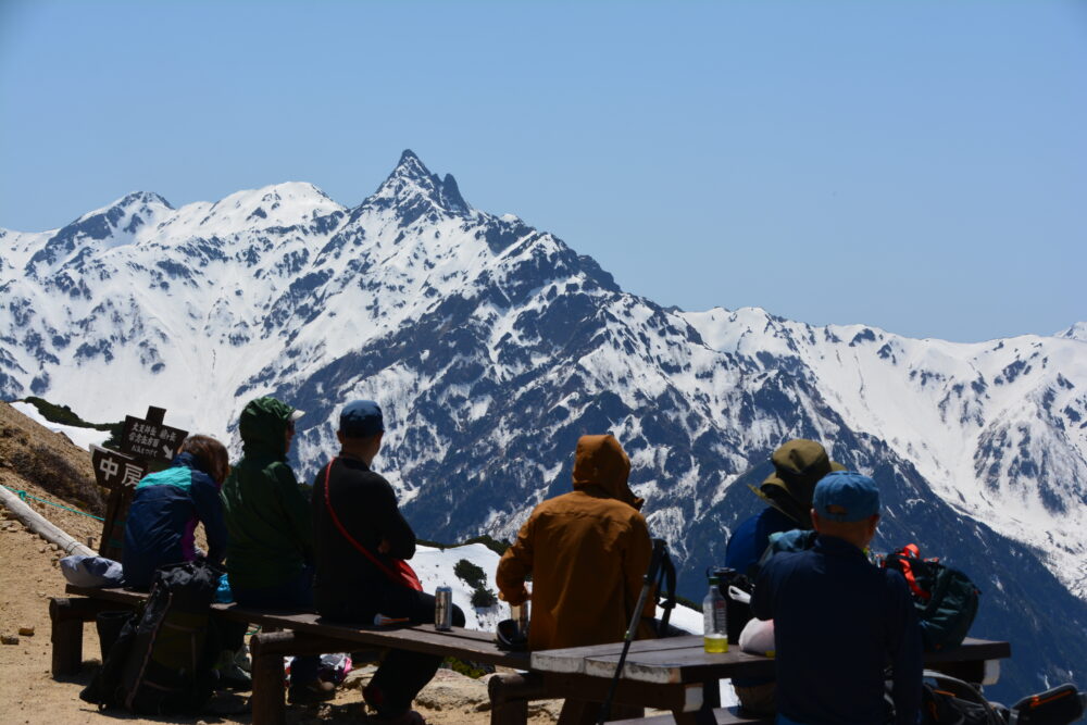 燕山荘前のベンチに座る登山者と槍ヶ岳