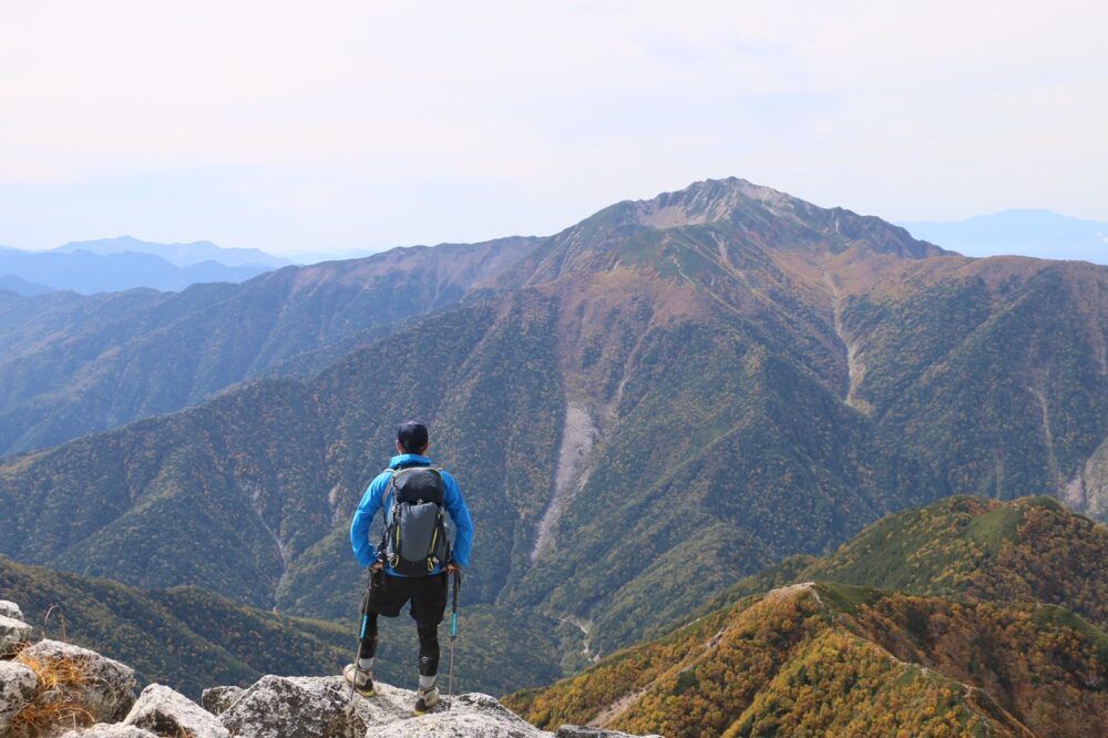 甲斐駒ヶ岳山頂から仙丈ヶ岳を眺める登山者