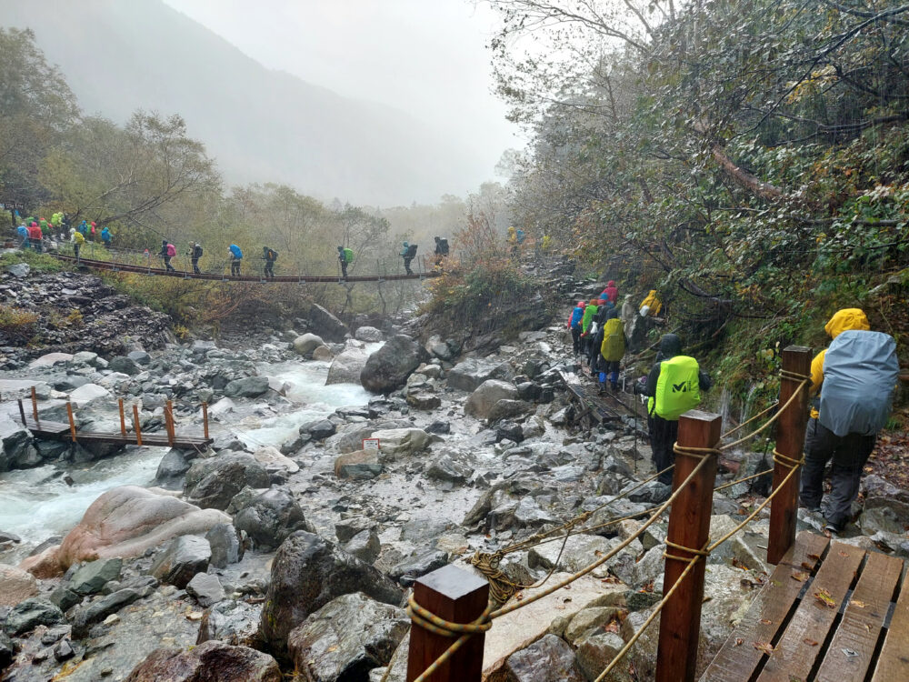 雨の本谷橋を歩く登山者行列