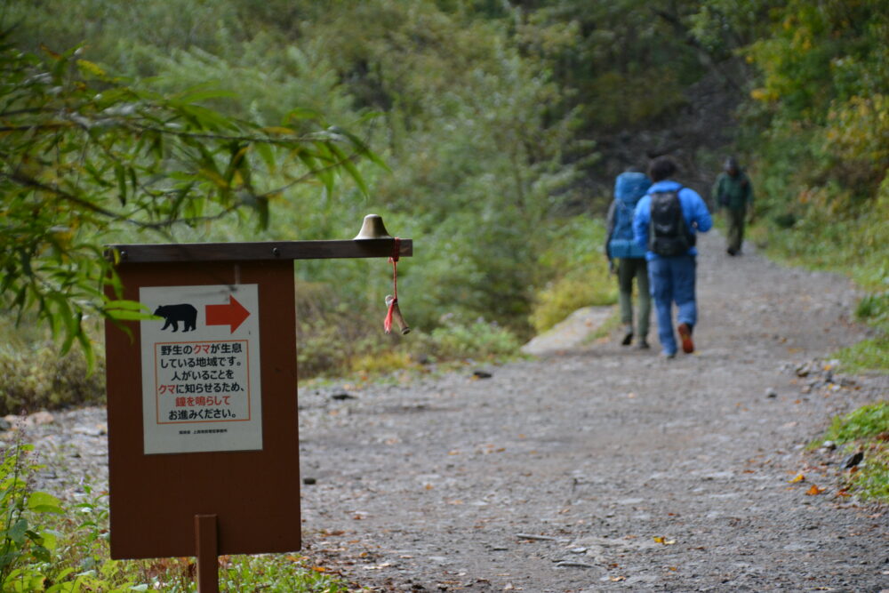 上高地の林道を歩く登山者とクマよけの鐘