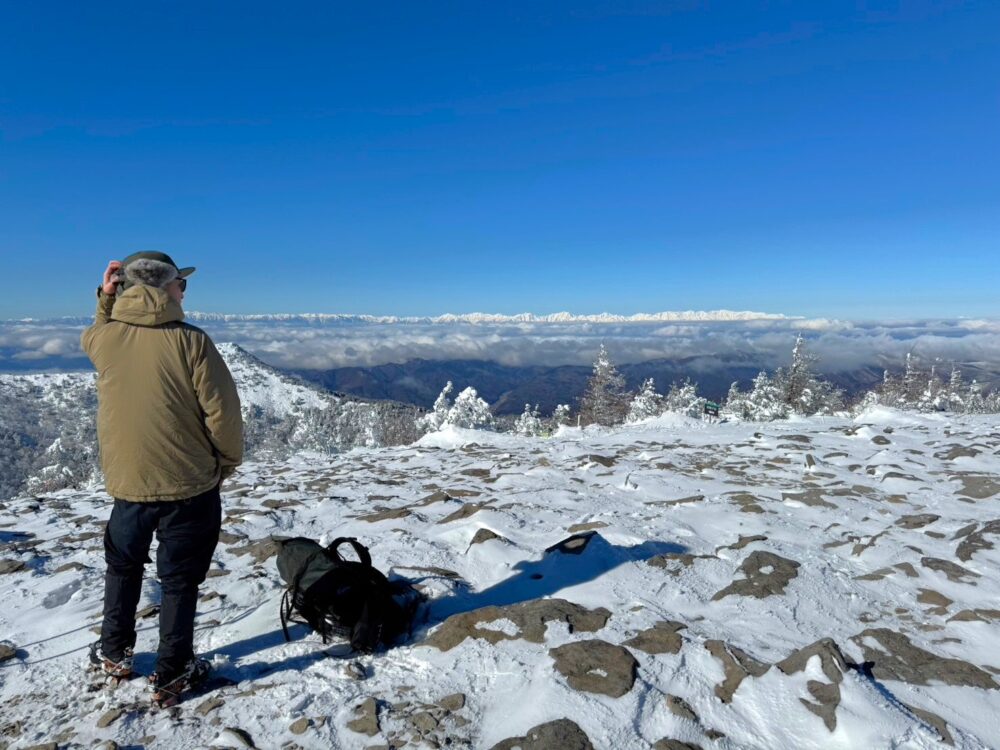 湯ノ丸山山頂で北アルプスを眺める登山者