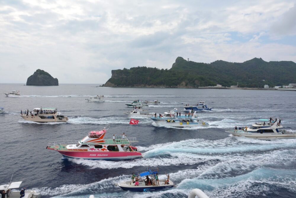 父島から出港したおがさわら丸と並走して進むツアーボートやクルーズ船