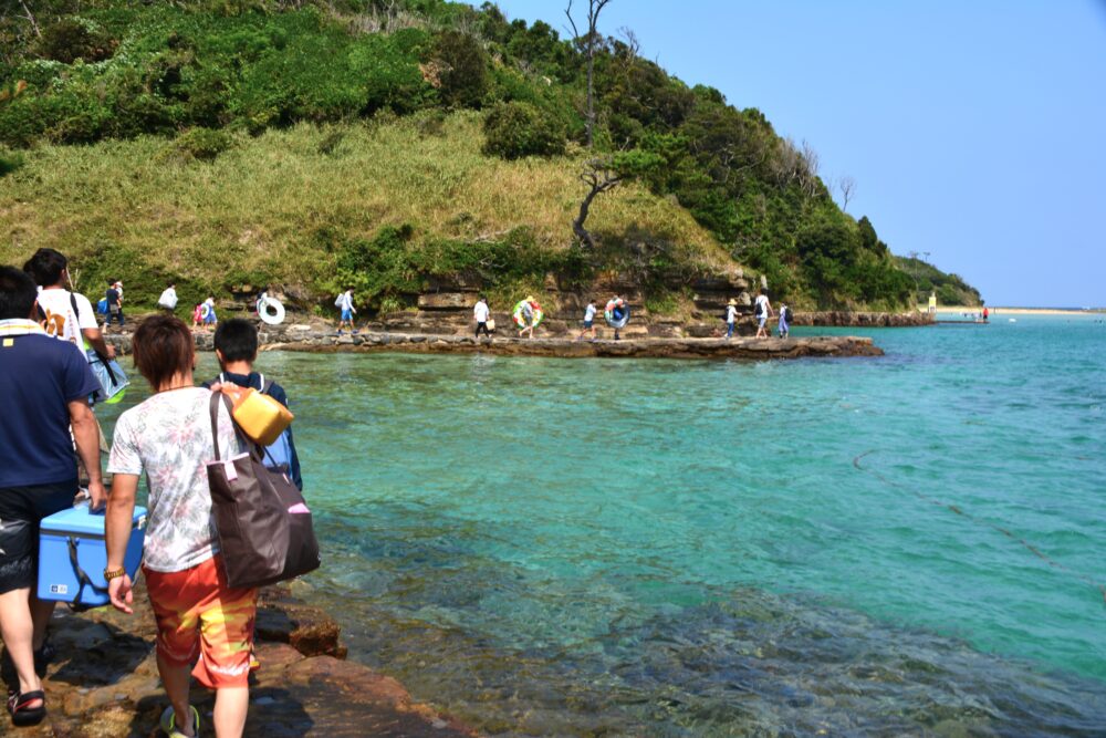 辰ノ島の船着き場からビーチへ歩いている人々