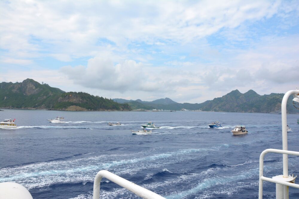 父島から出港したおがさわら丸と並走して進むツアーボートやクルーズ船