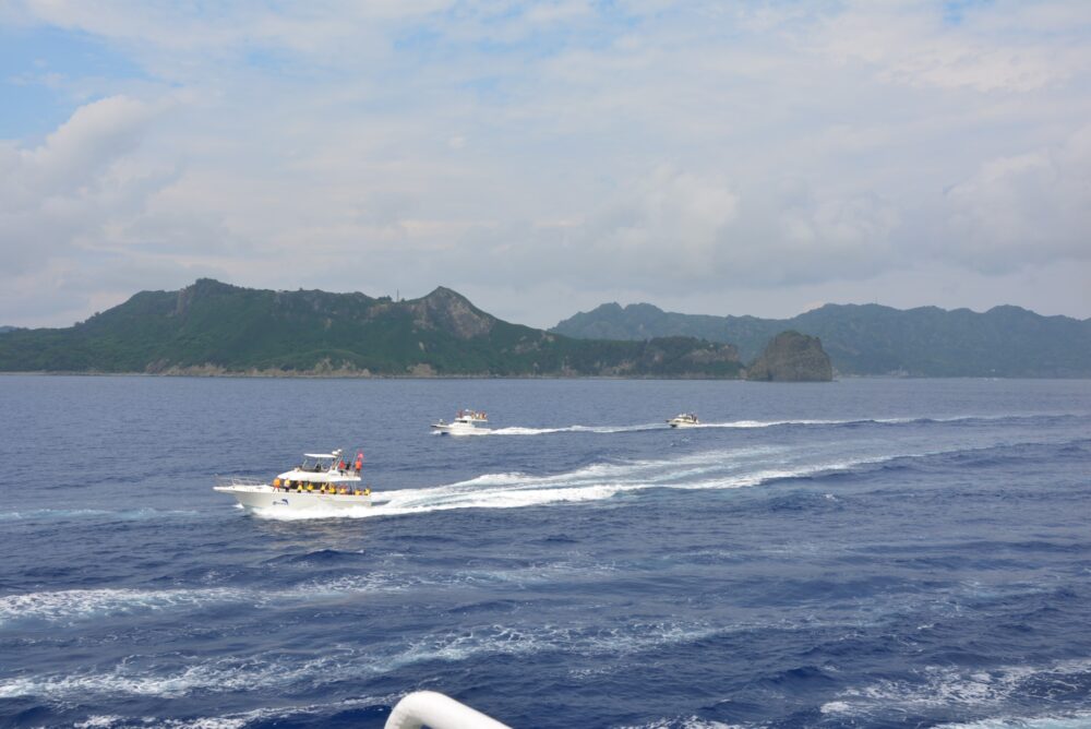 父島から出港したおがさわら丸と並走して進むツアーボートやクルーズ船