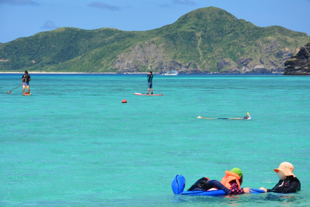 座間味島の阿真ビーチでSUPや海水浴をしてる人々