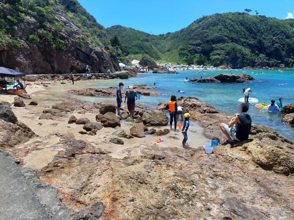 真夏の下田・九十浜海水浴場で磯遊びをしてる親子や家族