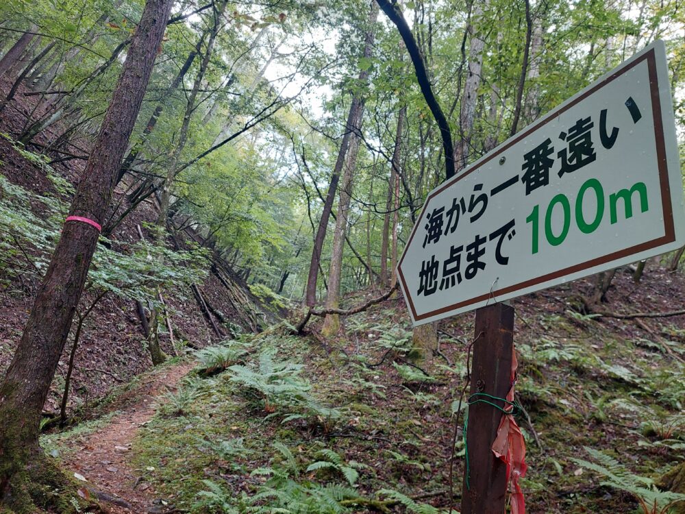 日本で一番海から遠い地点へ向かう登山道にある沢にある残り100mの看板
