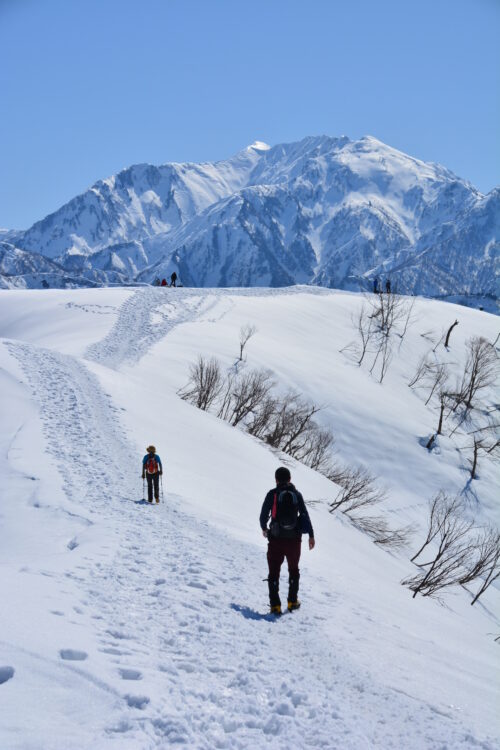 雪の大力山山頂から眺めた八海山と登山者