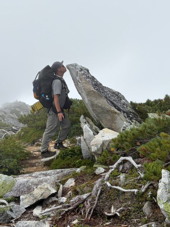 常念岳のライチョウに見える岩とキスをする登山者
