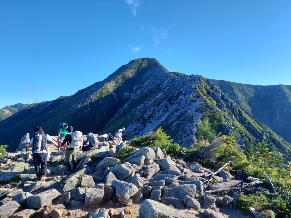 常念岳と休憩する登山者たち